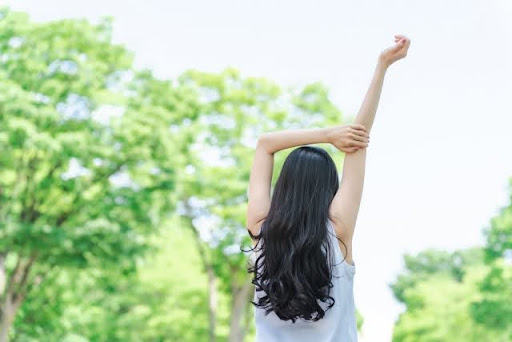 緑の中で右手を伸ばす女性